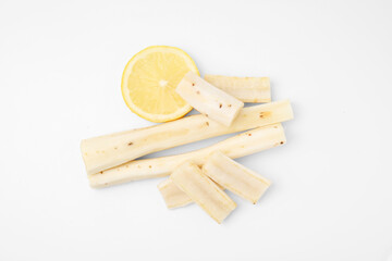 Cut raw salsify roots and lemon on white background, flat lay