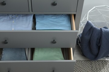 Sorting and organizing. Chest of drawers with different folded clothes indoors