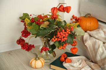 Beautiful autumn composition with different pumpkins and book indoors