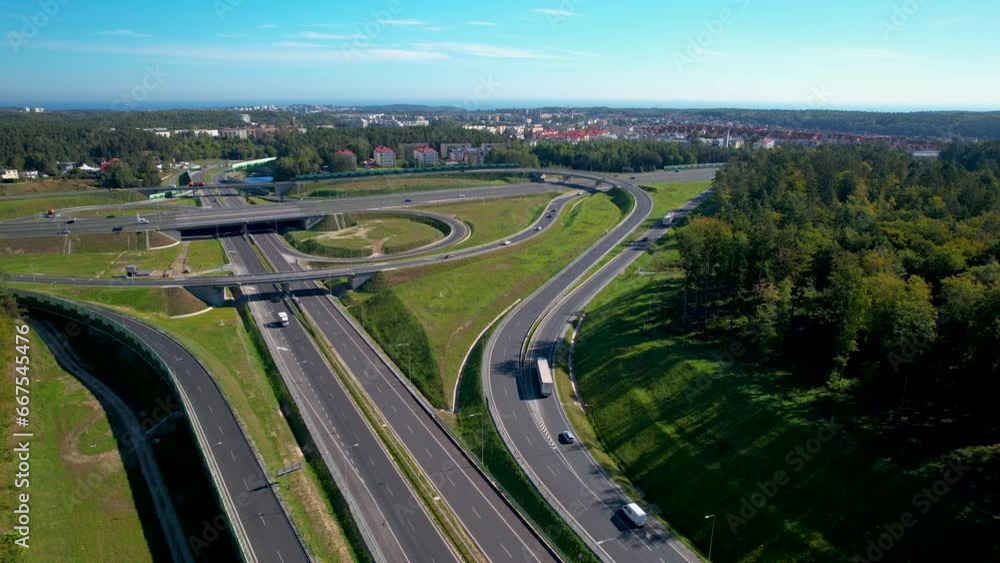 Poster aerial view of a sprawling highway interchange with multiple lanes and overpasses, surrounded by tre