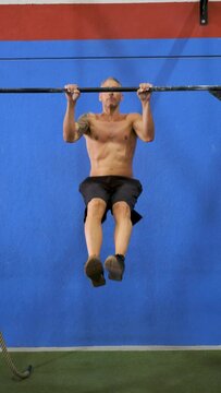Man doing pull ups on bar in cross fit training gym. CrossFit, fitness and sport.