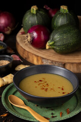 Close-up of plate of zucchini cream with onions, bread and garlic on black background, vertical, with copy space