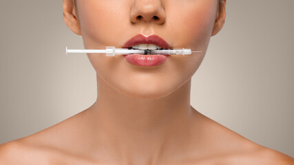 Young european woman holding injection syringe in mouth