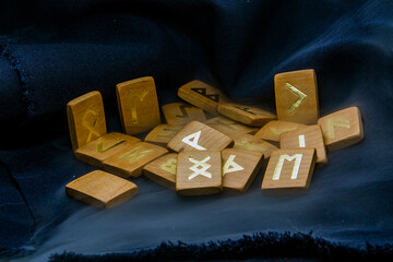 Wooden runes lie on a dark background close-up	
