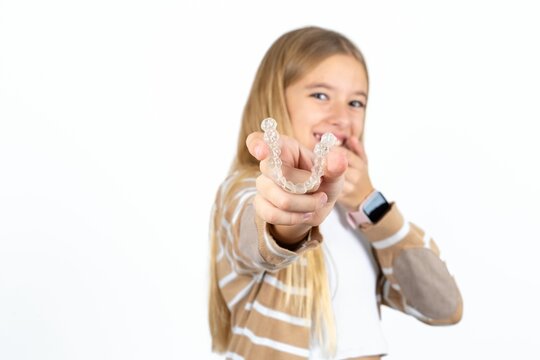 Happy Beautiful teen blonde girl holding and showing at camera an invisible aligner while laughing. Dental healthcare and confidence concept.