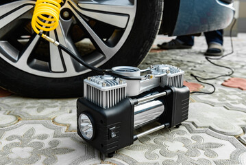 Close up of automobile compressor with manometer inflating car wheel. - obrazy, fototapety, plakaty