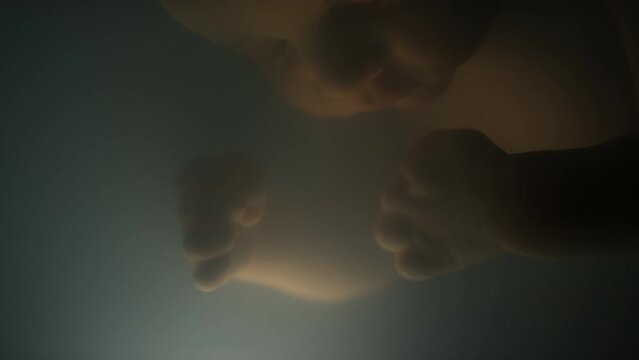 Macro closeup of anxious sleeping lab growing foetus pulling hand inside artificial womb