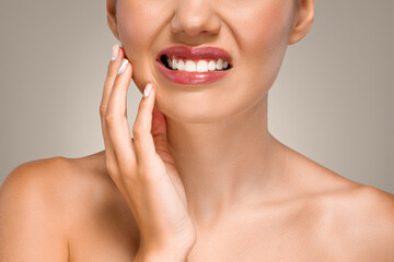Sad young european lady puts hand to cheek, suffering from toothache, tooth sensitivity