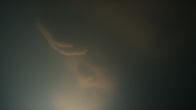 Closeup of sleeping lab grown child turning around in opaque amniotic fluid inside artificial uterus