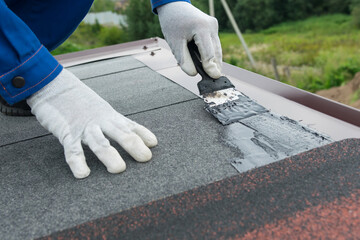 close-up, application of mastic on the roof, on the soft roof, between the metallic tint to eliminate leakage, and proper installation