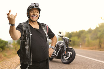 Mature biker with a leather vest gesturing a rock and roll sign