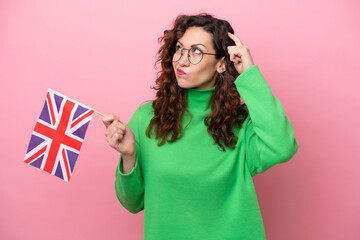 Young caucasian woman holding English flag isolated on pink background having doubts and with...