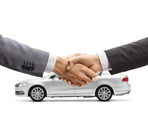 Men shaking hands in front of a silver car