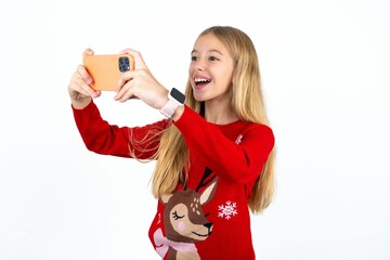 Beautiful caucasian teen girl wearing christmas sweater taking a selfie to post it on social media...