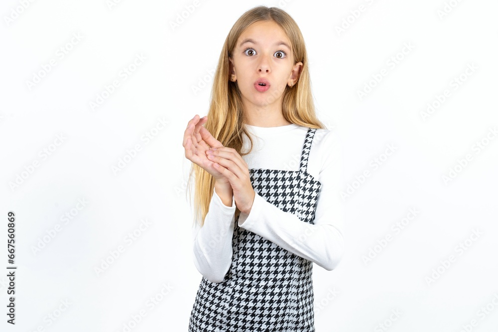 Wall mural surprised emotional beautiful caucasian teen girl rubs palms and stares at camera with disbelief