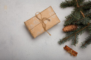 Blue fir tree branch with big cone, wrapped present box and cinnamon sticks on white wooden background. Christmas blank card, copy space