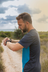 sportsman looking at his smartwatch after exercising in nature