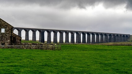 A bridge over a steep cliff in a scenic landscape, Ribblehead viaduct, North Yorkshire, UK