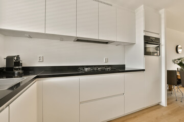 Fototapeta premium a modern kitchen with white cabinets and black counter tops in the center of the image is a small dining table