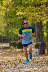 Fototapeta premium Portrait of a middle-aged man running in the park on an autumn day.