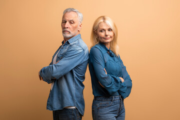 Frustrated senior woman and man couple fighting on beige background