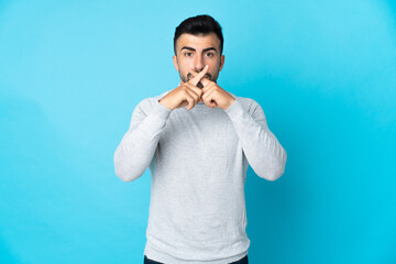 Caucasian man over isolated blue background showing a sign of silence gesture