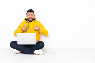 Caucasian man sitting on the floor with his laptop with surprise facial expression