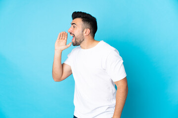 Caucasian man over isolated blue background shouting with mouth wide open to the side