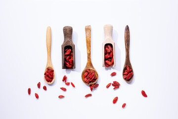 Dried goji berries on wooden spoons isolated on white background.
