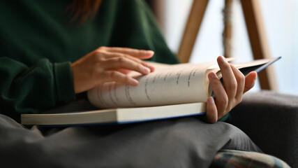 Young woman reading book while relaxing and enjoying favorite novel at home