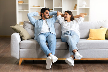 Cheerful Indian couple enjoying a moment on a couch in a cozy living room