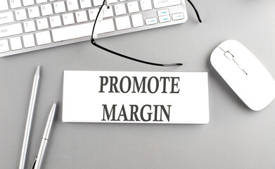 PROMOTE MARGIN text on paper with keyboard on grey background