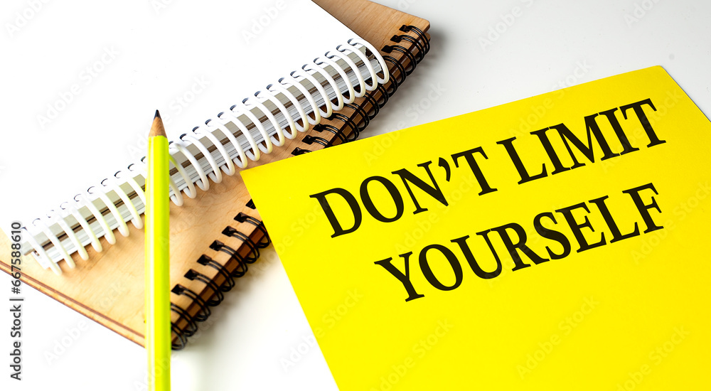 Aufkleber don't limit yourself text written on a yellow paper with notebook