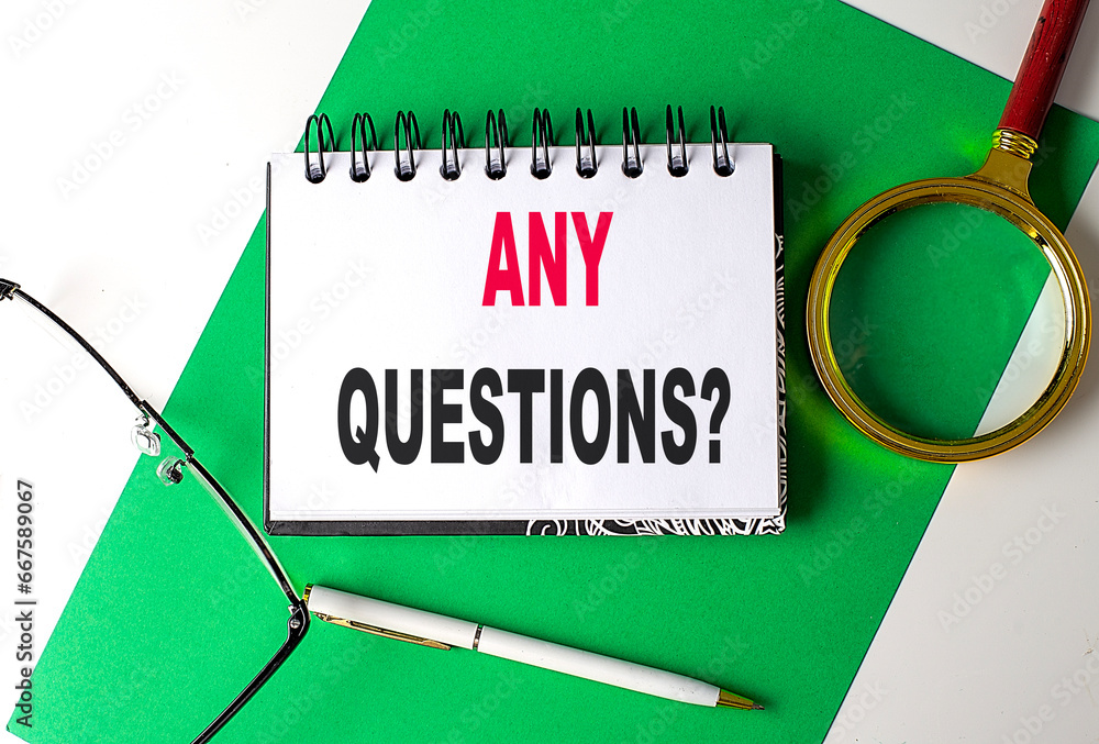 Aufkleber any questions text on notebook on green paper