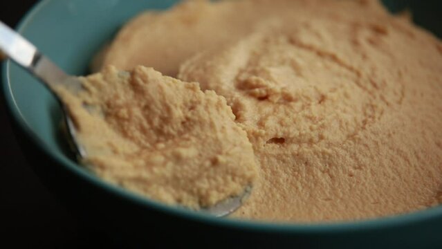 An appetizing video featuring a close-up of delicious homemade hummus in a vibrant blue bowl