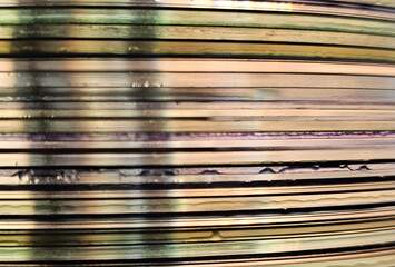 Close-up to interesting abstract patterns created by the rays of sunlight penetrating through a pile of CD arranged on the desk, Lodz, Poland.