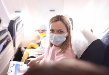Young woman in protective mask making selfie in cabin of plane. Flight rules for passengers during...