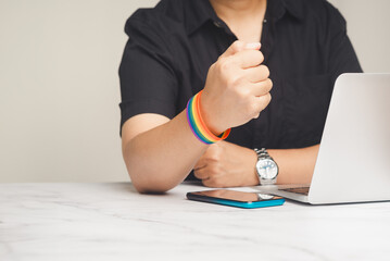 Close-up of a rainbow wristband in a hand while sitting at the table.