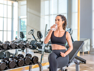 Fototapeta na wymiar Exhausted woman in sportswear sitting at fitness training in .sporty athletic woman warm up training sitting near treadmill look aside in gym indoor Workout sport motivation