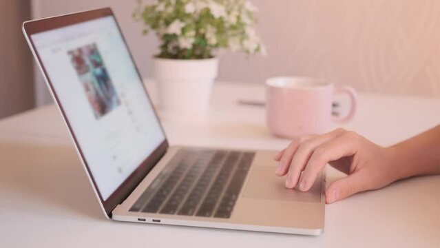 Young woman fingers using touchpad close up, at laptop on white table, in front modern monitor, looking photo, work at home, side view. Organizing work from home and time management.