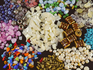 A variety of beads made of natural stone, glass, mother-of-pearl, ceramics and metal on a black background