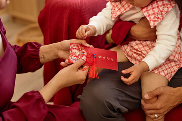 Close up of Asian woman giving red envelope to little girl as Good fortune tradition for Chinese...