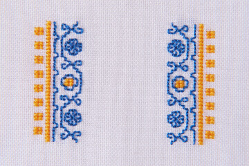 Element of Handmade Embroidery on White Linen by blue and yellow Cotton Threads. Craft Design - obrazy, fototapety, plakaty