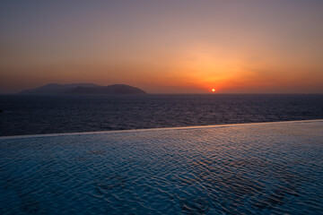 View of a swimming pool overlooking the Aegean Sea and a spectacular sunset in Ios Greece