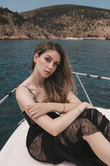 beautiful woman with blond hair in luxurious black dress relaxing on the yacht in the Mediterranean sea