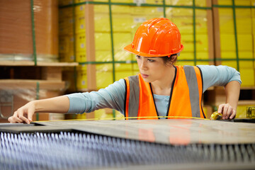 female factory worker using tape measure and measuring steel in the factory