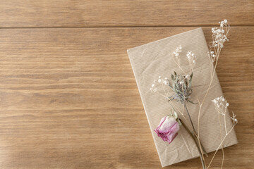 Dried roses and babies' breath　flowers accompanied by a book on a wooden table