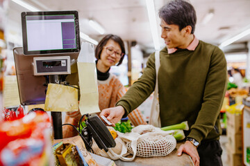 Man buying fresh produce from woman at supermarket counter