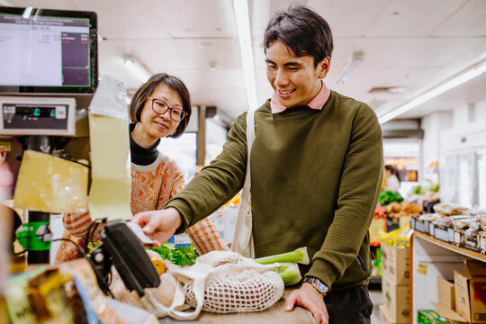 Man buying fresh produce from woman at supermarket counter