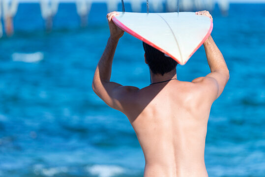 man carrying his surfboard on the head.